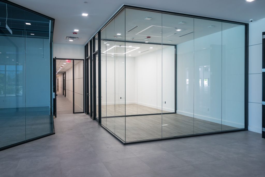 open office interior featuring sleek glass-walled rooms with black frames
